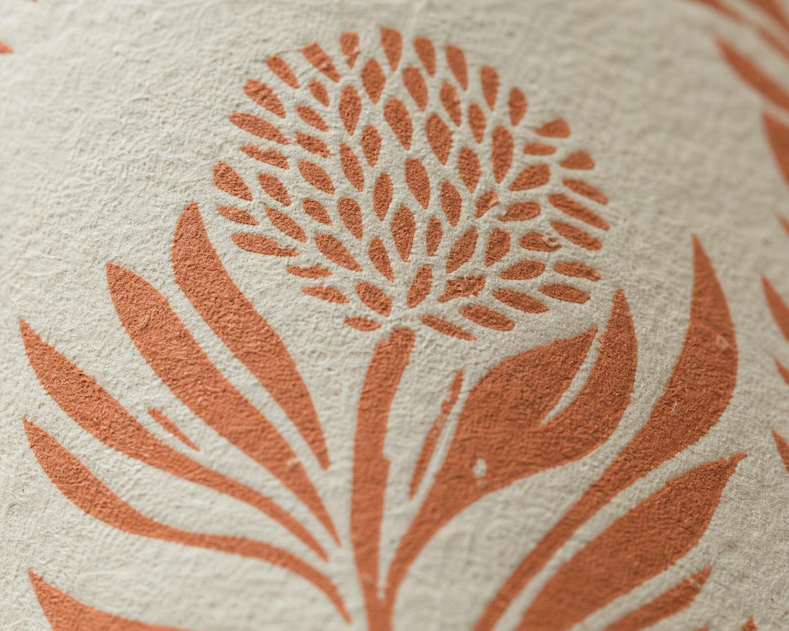 Macro detail of hand-block-printed sienna botanical motif on heavy cream paper