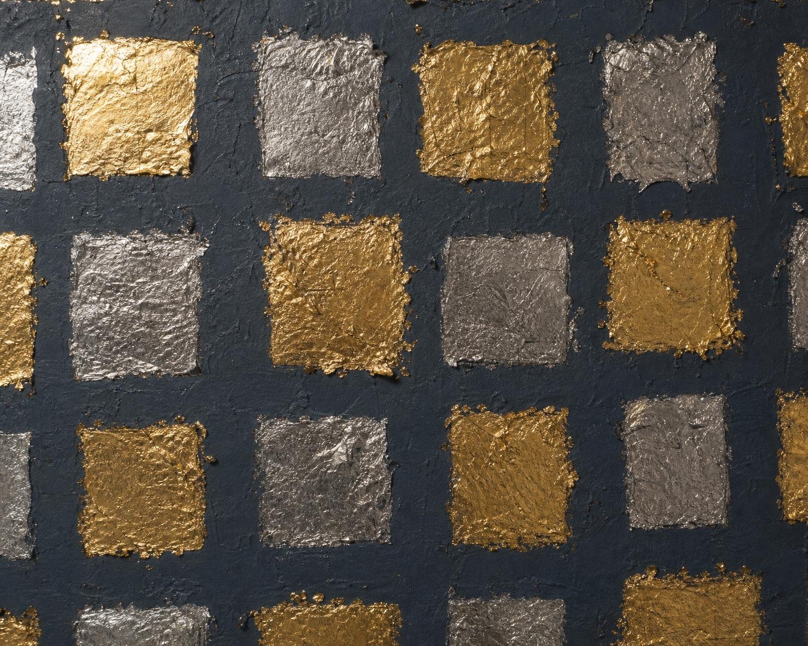 Macro of hand-applied gold and pewter leaf squares on a charcoal ground wallpaper