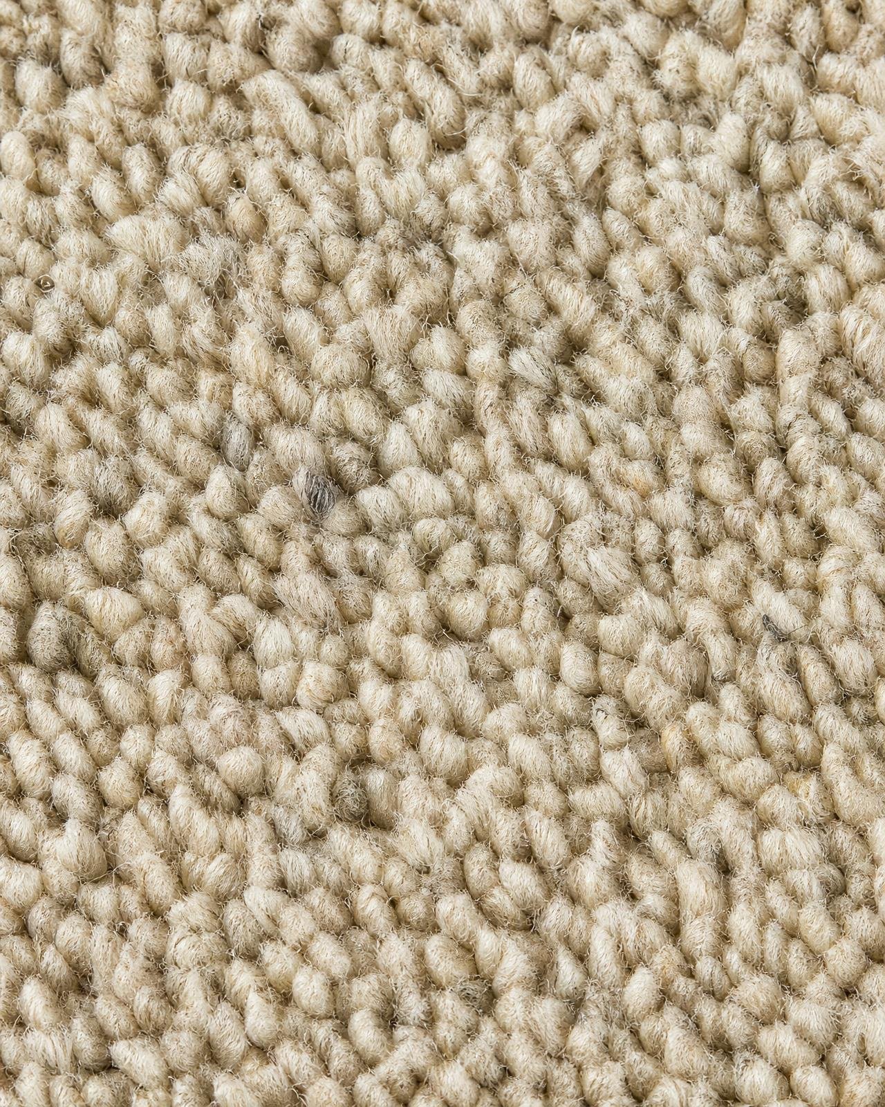 Macro of dense wool loop carpet in warm oatmeal with visible fibres