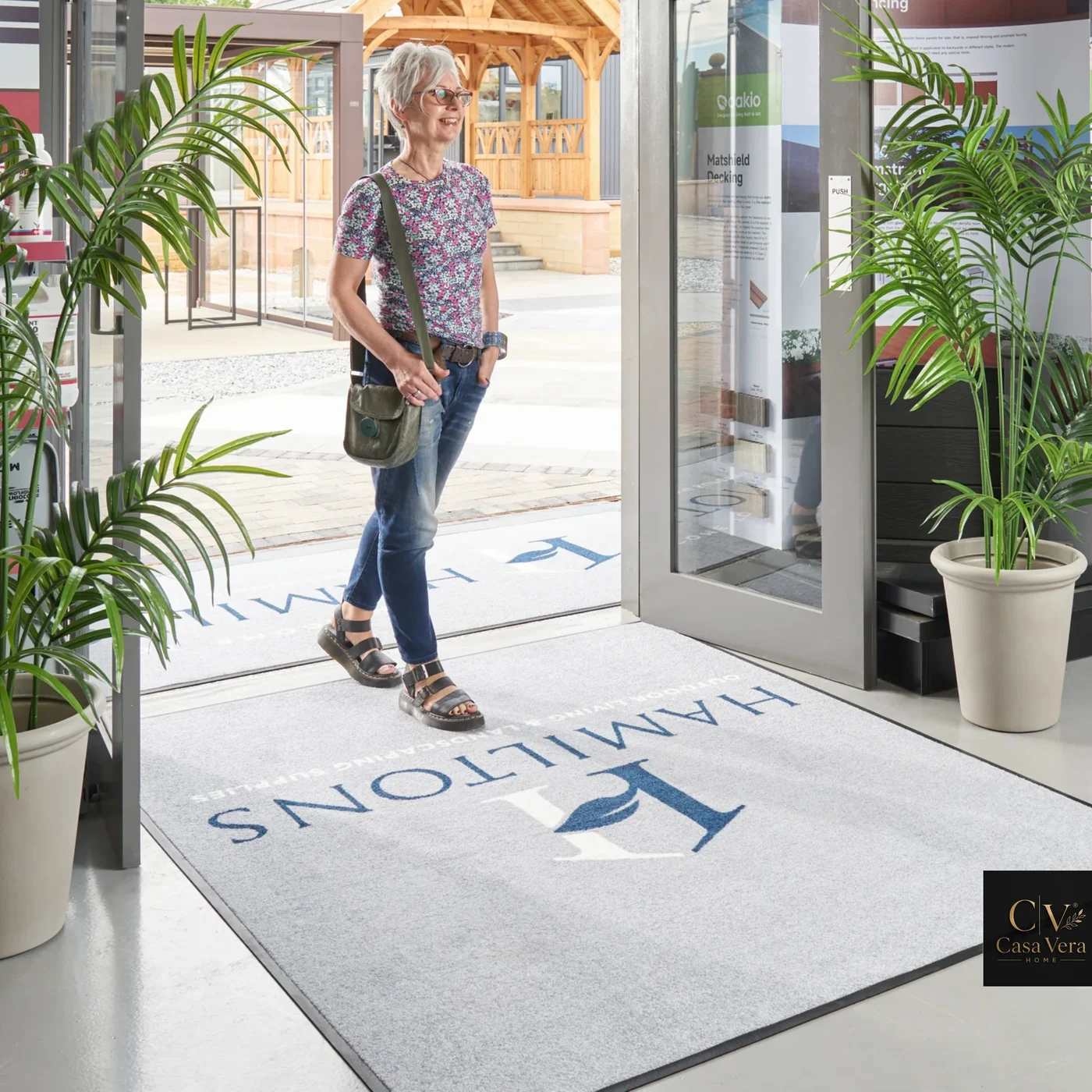 Pale printed logo mat laid inside a glazed commercial entrance with a visitor walking in